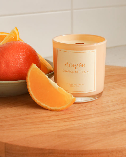 Orange chiffon candle. orange candle with white label surrounded by oranges in a kitchen.